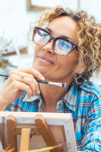 Woman artist with a dreamy expression in her art studio, sketching and painting on canvas, imagining her future successes while focusing on her craft, enjoying every moment of her creative process photo