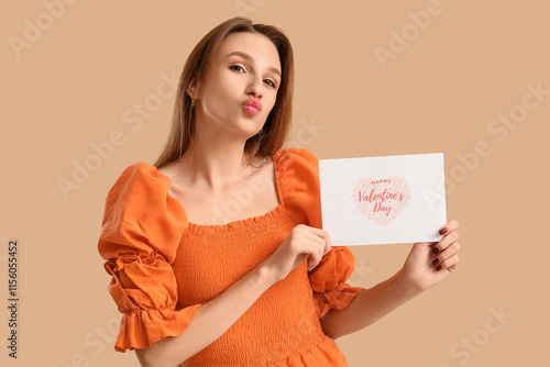 Beautiful young woman holding greeting card with text HAPPY VALENTINE'S DAY on beige background