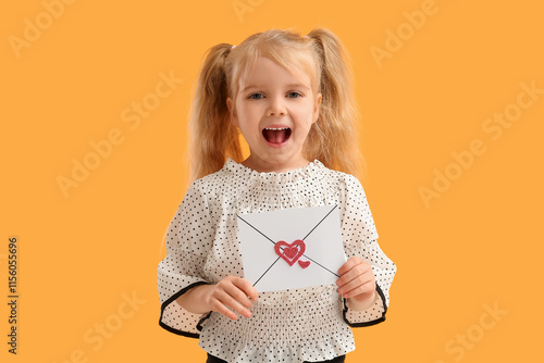 Cute little girl holding envelope with hearts on yellow background. Valentine's Day celebration