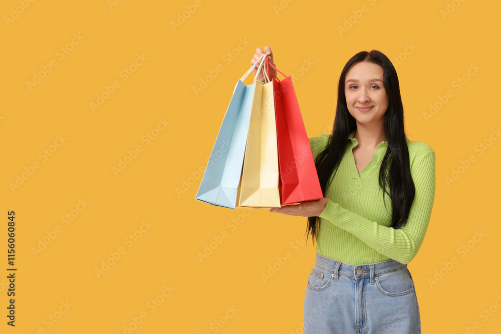 Beautiful young woman with shopping bags on yellow background. International Women's Day Beautiful young woman with shopping bags on yellow background. International Women's Day