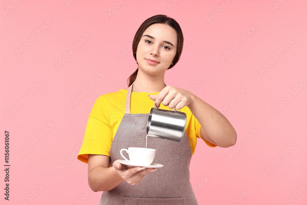 Girl in apron pouring milk from pitcher into cup of coffee on pink background. Work for teenagers Girl in apron pouring milk from pitcher into cup of coffee on pink background. Work for teenagers