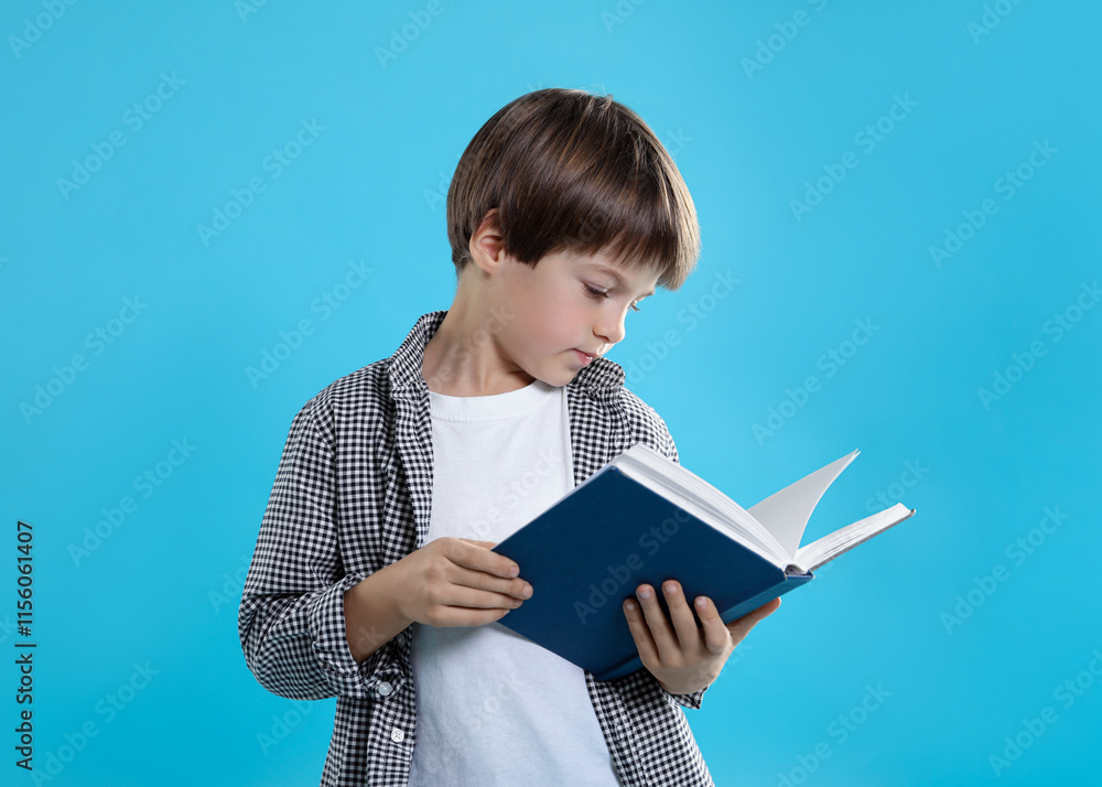 Obraz premium Learning alphabet. Little boy with book on light blue background