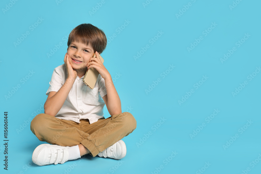 Cute little boy talking on smartphone against light blue background, space for text Cute little boy talking on smartphone against light blue background, space for text