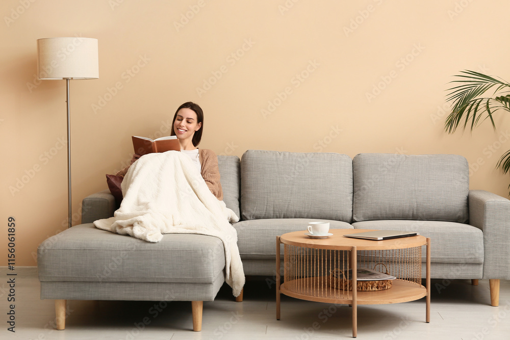 Young woman reading book on sofa in stylish living room Young woman reading book on sofa in stylish living room