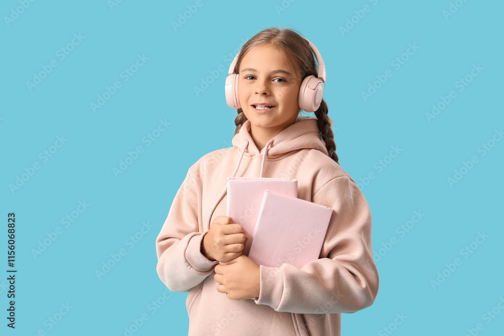 Cute schoolgirl in headphones with books on blue background Cute schoolgirl in headphones with books on blue background