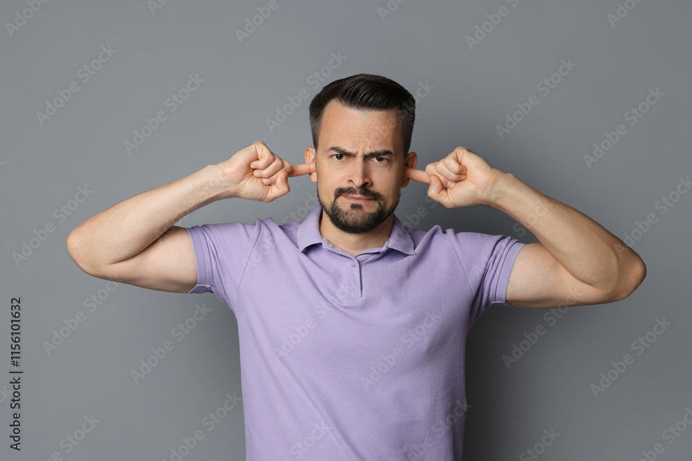 Man covering his ears with fingers on grey background Man covering his ears with fingers on grey background