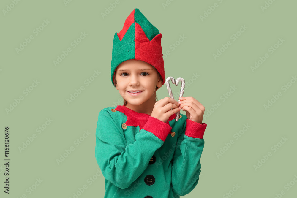 Cute little girl in elf costume with candy canes on green background. Christmas celebration Cute little girl in elf costume with candy canes on green background. Christmas celebration