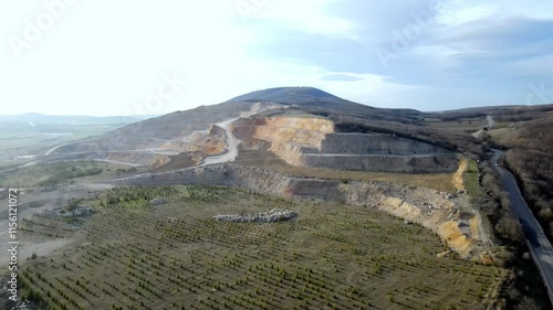 A large cement mine site and old mining areas that have been rehabilitated with pine trees. Slow motion with aerial video