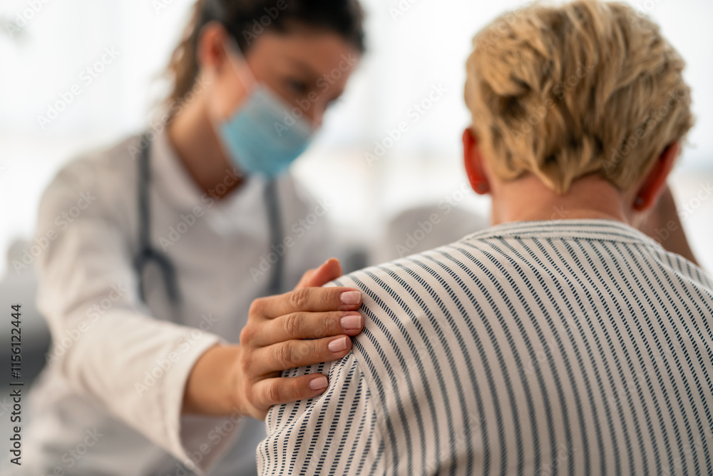 Obraz premium Female Caucasian doctor in white coat and medical mask provides compassionate care to senior Caucasian patient during professional home healthcare consultation.