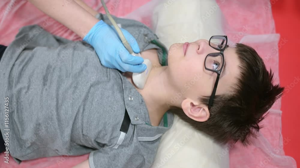 Doctor making ultrasound of thyroid gland for boy using scanner machine ...