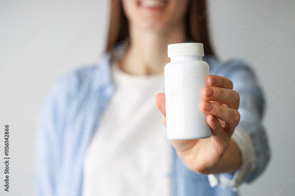 Woman holding medical bottle with pills on light background, closeup Woman holding medical bottle with pills on light background, closeup