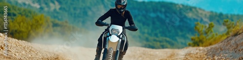 A woman is riding a dirt bike on a dirt road. The road is rocky and bumpy, and the woman is wearing a helmet and riding gloves. The scene is adventurous and exciting photo