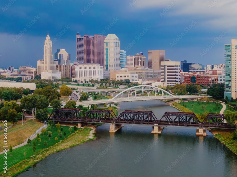 Naklejka premium Aerial view of the Columbus, OH skyline, featuring the Scioto River and bridges. Cityscape with modern and historic architecture. A tranquil urban scene. SCIOTO RIVER, COLUMBUS, OHIO, UNITED STATES