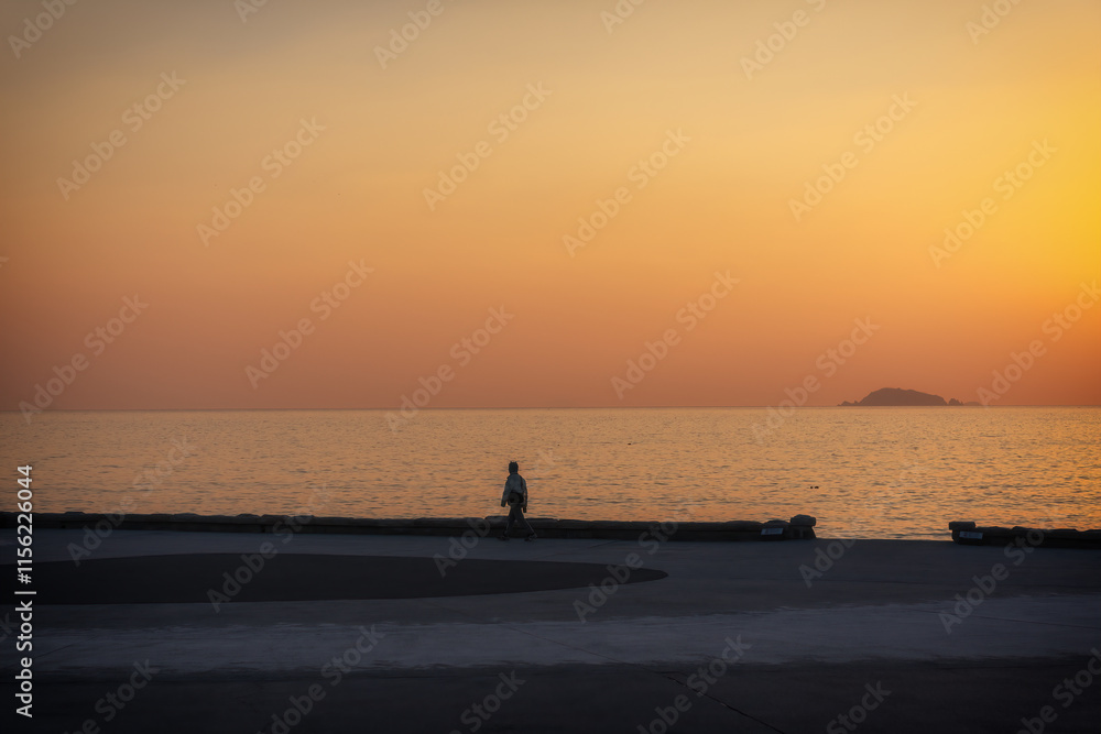 Fototapeta premium Tranquil Sunset Stroll Along the Water's Edge