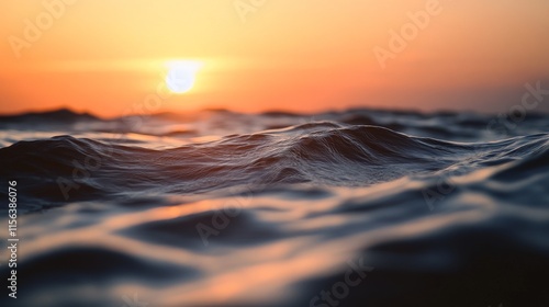 The sun is setting over the ocean, casting a warm glow on the water. The waves are choppy, and the water is a deep blue color. The scene is serene and peaceful