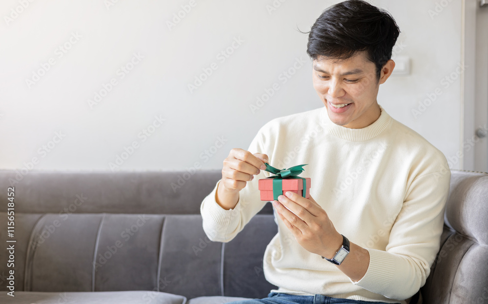 close up young man hand try to open red gift box with green ribbon to send to someone special in festive season for people lifestyle concept close up young man hand try to open red gift box with green ribbon to send to someone special in festive season for people lifestyle concept