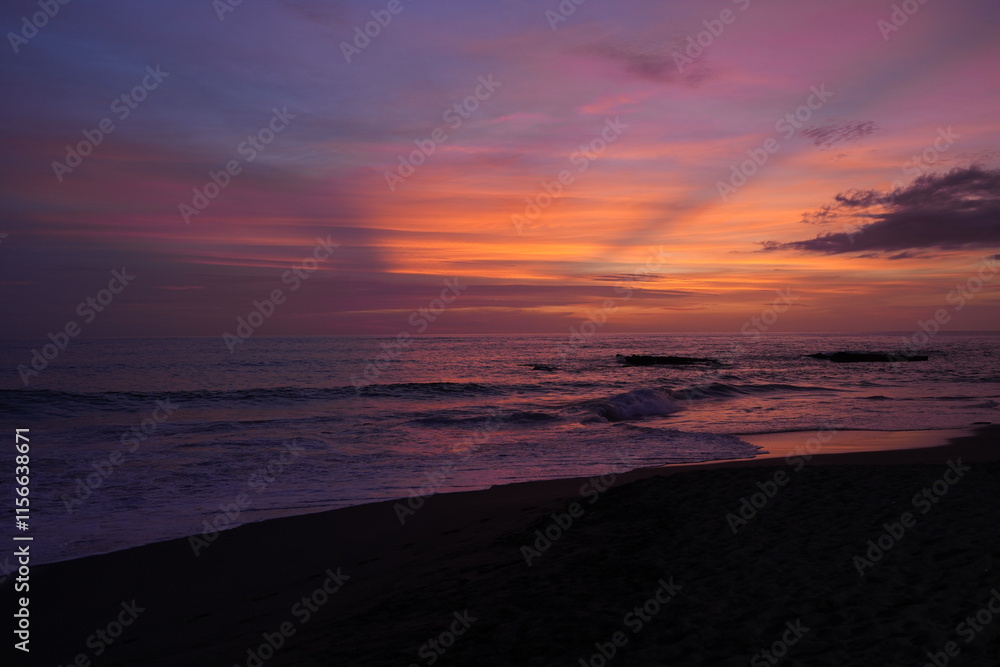 Fototapeta premium The ocean coast with a beautiful purple sunset. Waves in the sea. Wonderful mesmerizing landscape
