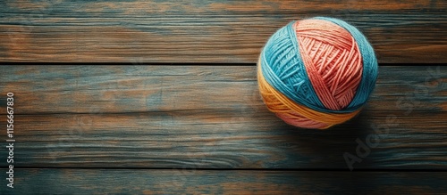 Colorful ball of yarn on rustic wooden surface showcasing texture and craftsmanship in a cozy domestic setting photo