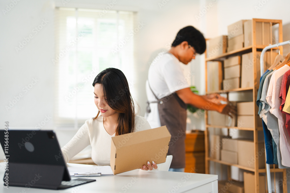 Startup small business owner working with computer at workplace. Freelance seller check product order. Packing goods for delivery to customer. Online selling. E-commerce. Online Shopping. Startup small business owner working with computer at workplace. Freelance seller check product order. Packing goods for delivery to customer. Online selling. E-commerce. Online Shopping.