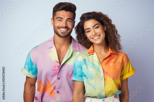 A man and woman are smiling for the camera in colorful Hawaiian shirts