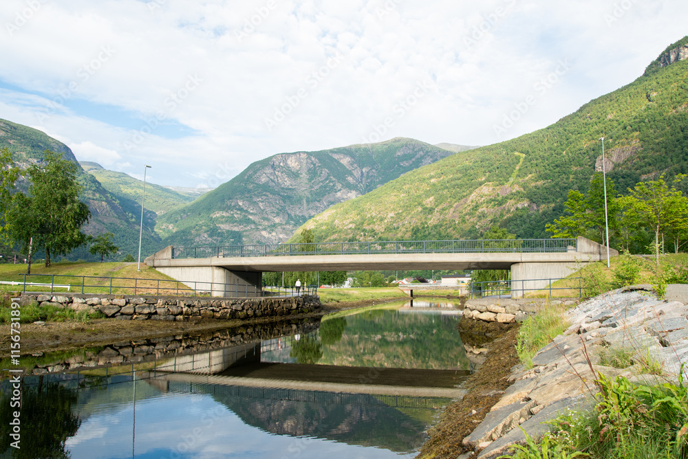 concrete bridge over a river with water like a mirror reflecting the beautiful Norwegian fjord mountains in the village of Lærdalsøyri. concrete bridge over a river with water like a mirror reflecting the beautiful Norwegian fjord mountains in the village of Lærdalsøyri.