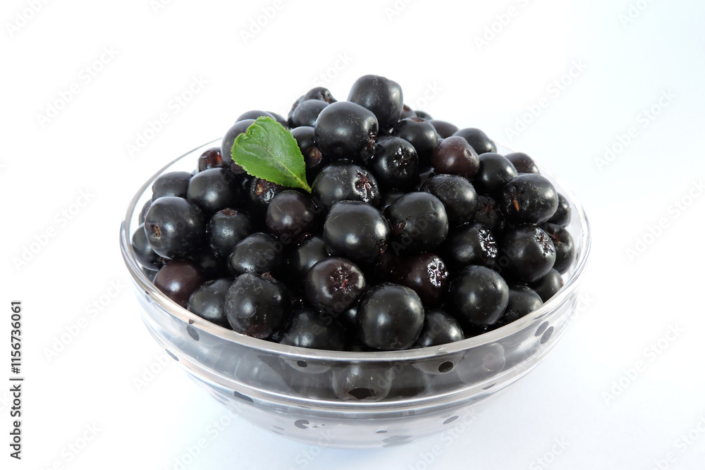 Fresh ripe aronia berries decorated with a green leaf in a glass bowl, white background, isometric view Fresh ripe aronia berries decorated with a green leaf in a glass bowl, white background, isometric view
