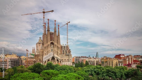 BARCELONA, SPAIN - NOVEMBER 9, 2024: Sagrada Familia under construction with cranes among trees and urban skyline in TL Barcelona