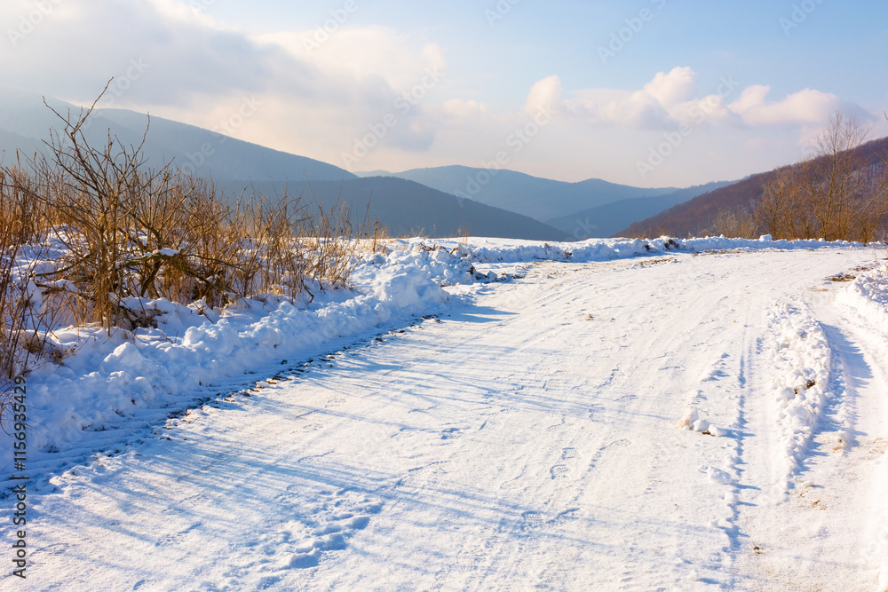 snow covered country road. beautiful view. sunny weather. countryside landscape in carpathian mountains in winter. clouds on the sky snow covered country road. beautiful view. sunny weather. countryside landscape in carpathian mountains in winter. clouds on the sky