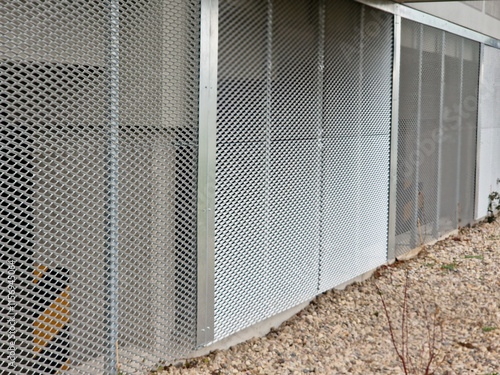 perforated metal sheet in the basement of the house in lining. trellis for climbing plants. the door of the electricity distribution box for the entire residential tower bock building photo