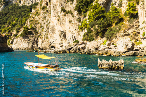 Unrecognizable man steering a small boat along the coast of the island of Capri, Italy.