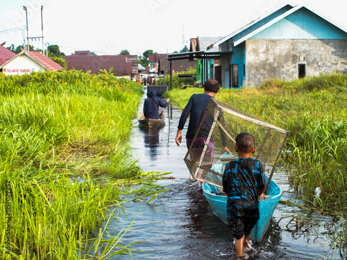 Flooded Village Scene: Men and Child in Boats, Carrying Cage, Lush Greenery