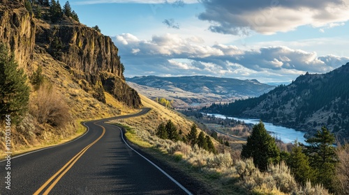 Fototapeta Naklejka Na Ścianę i Meble -  Scenic mountain viewpoint with winding road alongside river and foothills under a dramatic sky in a tranquil landscape setting
