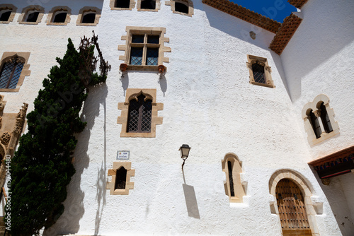 Obraz na płótnie Delivery man riding a scooter in a narrow street with white houses in sitges, spain w salonie