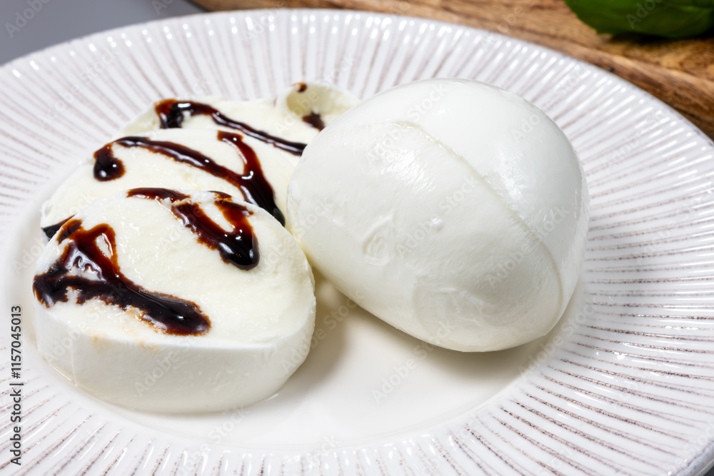 Fototapeta premium Tasty italian food, fresh white buffalo mozzarella soft cheese balls from Campania served with balsamic vinegar from Modena close up