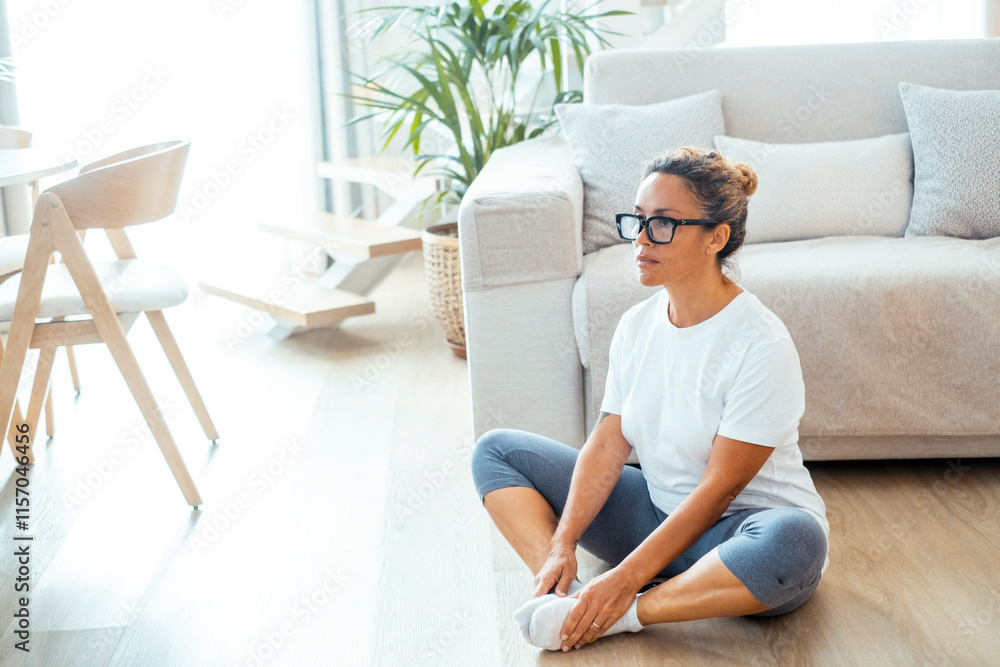 Woman performing a series of yoga poses and pilates exercises on the floor in her living room at home, stretching, strengthening muscles, and improving flexibility, as part of daily fitness routine Woman performing a series of yoga poses and pilates exercises on the floor in her living room at home, stretching, strengthening muscles, and improving flexibility, as part of daily fitness routine