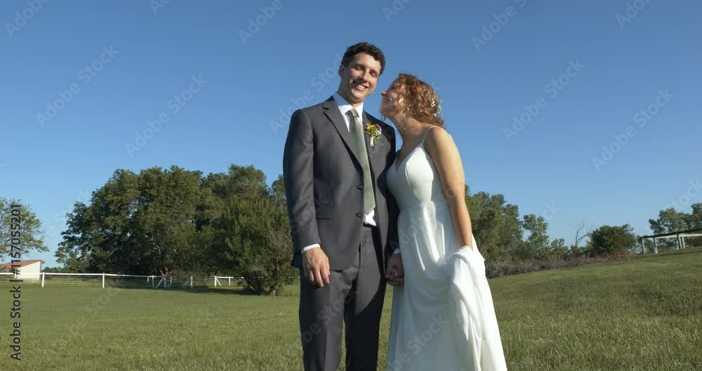 A joyful bride and groom kissing in a sunlit field, under tree shade, sharing smiles and laughter, as they celebrate their special day in a picturesque outdoor setting surrounded by nature. A joyful bride and groom kissing in a sunlit field, under tree shade, sharing smiles and laughter, as they celebrate their special day in a picturesque outdoor setting surrounded by nature.