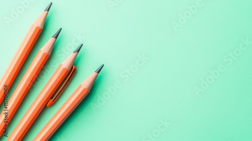 Vibrant orange pencils on a mint green background. photo