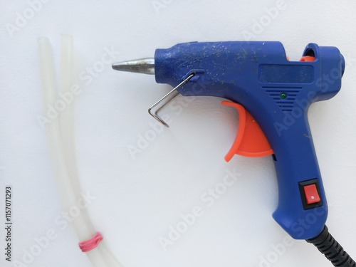 Hot glue gun and rods on a white table. Blue hot glue for gluing various objects, cardboard. photo