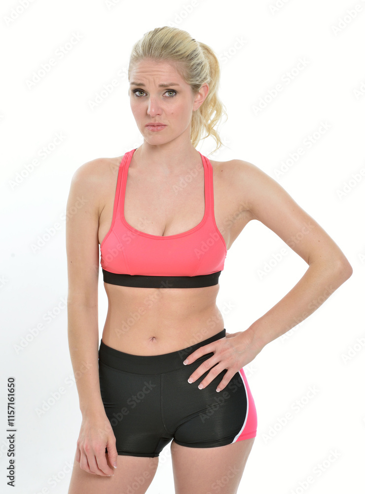 Sexy young Caucasian woman - fitness model - posing in lycra shorts and sports bra - looks concerned Sexy young Caucasian woman - fitness model - posing in lycra shorts and sports bra - looks concerned