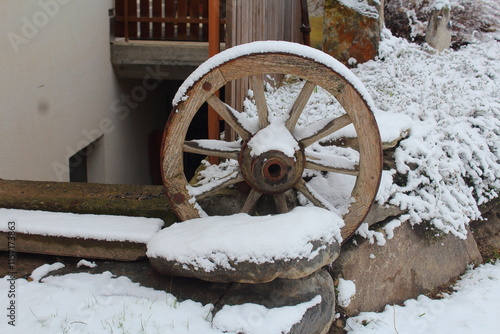 Primo piano di una ruota di carro ricoperta dalla neve utilizzata come ornamento per una casa di montagna