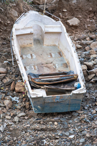 An old broken tourist speed boat lies abandoned out of the water on the land. Its poor condition and broken seats illustrate the passage of time at Tehri Lake. photo