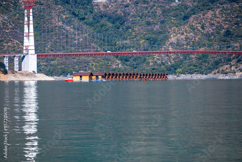 Floating huts are visible in Tehri Lake, with a suspension bridge on the other side. This unique feature adds to the charm and attraction of the area. photo