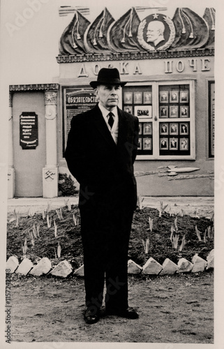 Vintage portrait of an elderly man in the uniform of a USSR railway worker near the honor board. The inscription on the Russian Honor Board. Retro photo from 1960. photo