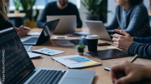 A team of professionals working together on laptops, with papers, pens, and coffee cups scattered across a sleek, minimalist desk.