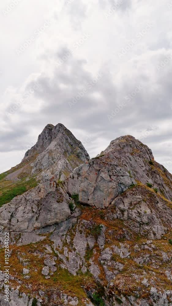 Approaching the rocks covered with lichens. Flight along the bare mountains range. Cloudy sky at backdrop. Vertical video. Approaching the rocks covered with lichens. Flight along the bare mountains range. Cloudy sky at backdrop. Vertical video.