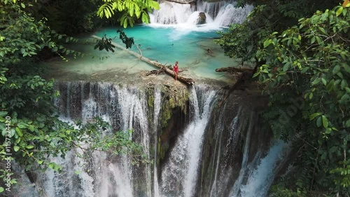 Traveller woman on cascade waterfalls with clear water in Sulawesi. Scenic waterfall in Luwuk, drone view photo