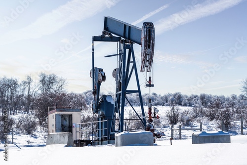 Abandoned oil and gas well along the Albertan Foothills with a pump jack no longer working producing natural resources in Alberta Canada. photo