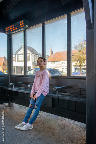 Young girl waiting at a cozy bus stop on a sunny afternoon a charming bus stop, sunlight streaming through large windows, revealing a quiet street and picturesque buildings outside.