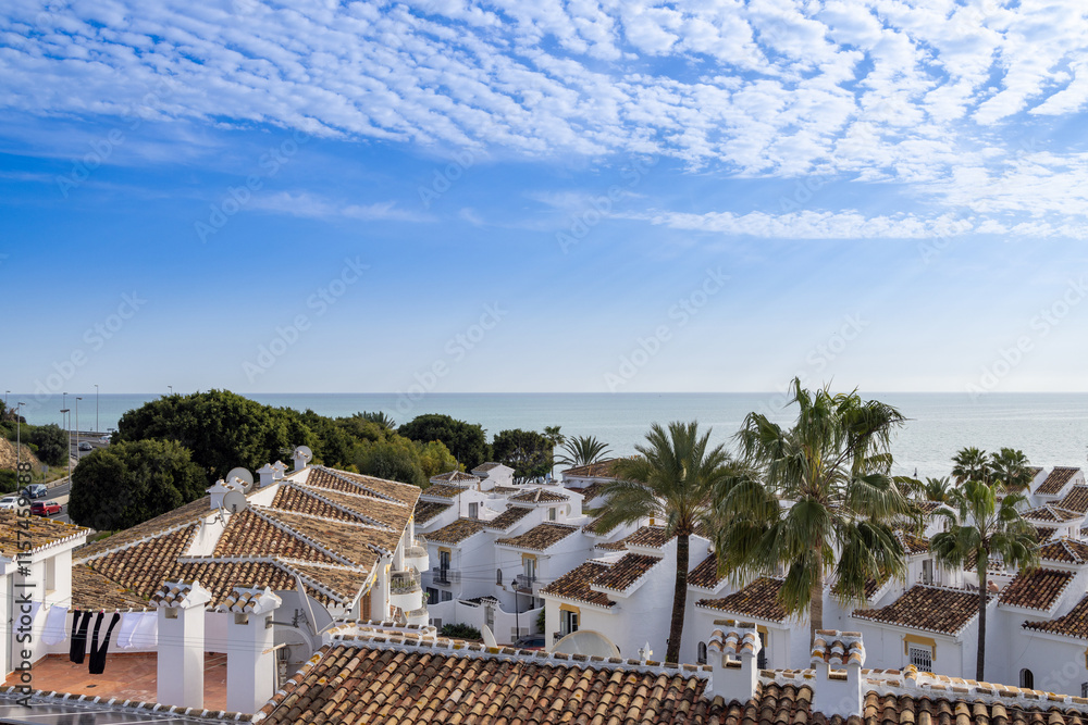 Photo from above of a typical small Spanish apartment block and Spanish homes and houses leading on to the beautiful beach front seeing the blue ocean on a sunny day