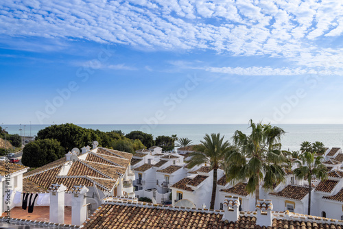Obraz na płótnie Photo from above of a typical small Spanish apartment block and Spanish homes and houses leading on to the beautiful beach front seeing the blue ocean on a sunny day w salonie